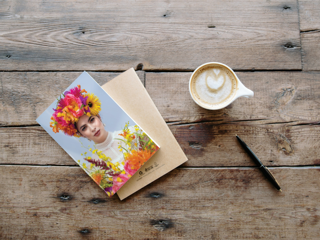 Greeting card on a wood table sitting next to a coffee mug and a pen