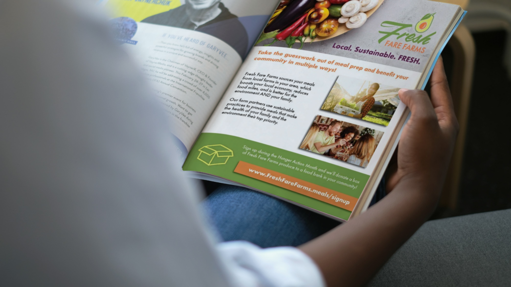 person holding a magazine that is open to an advertisement